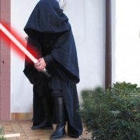 Mein Sith-Kostüm mit Anakin-Lichtschwert in rot (Photoshop, ich mag dich). Die Haube ist wirklich riesig und die gesammte Robe ist wirklich fast so tief wie in den Filmen. Zwei Zentimeter kürzer allerdings, weil mir der Verkäufer die Robe nicht so lang wie in den Filmen verkaufen wollte wegen seiner Versicherung, die es nicht erlaubt wegen der langen Robe im Treppenhaus zu stolpern und den Kunden das Genick dabei zu brechen. War einfach ein netter Kauf.